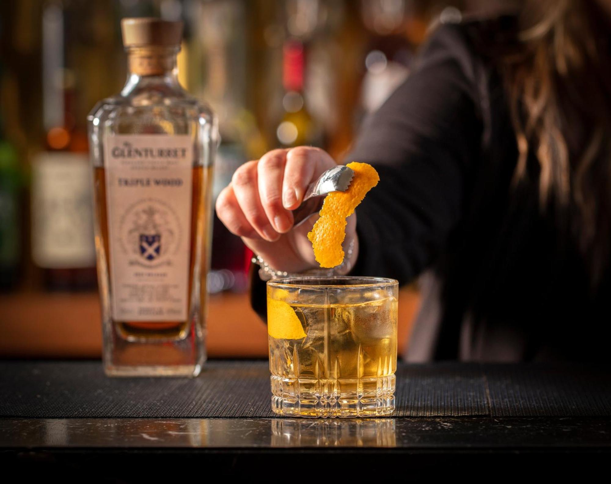 Schloss Roxburghe, Part Of Destination By Hyatt Kültér fotó A bartender adding a lemon twist to a glass of GINfinity